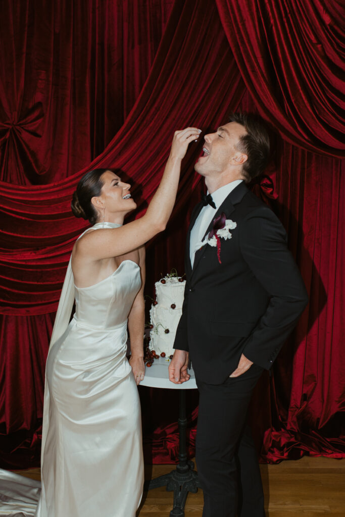 Emily and Patrick embracing during red draped editorial wedding shoot